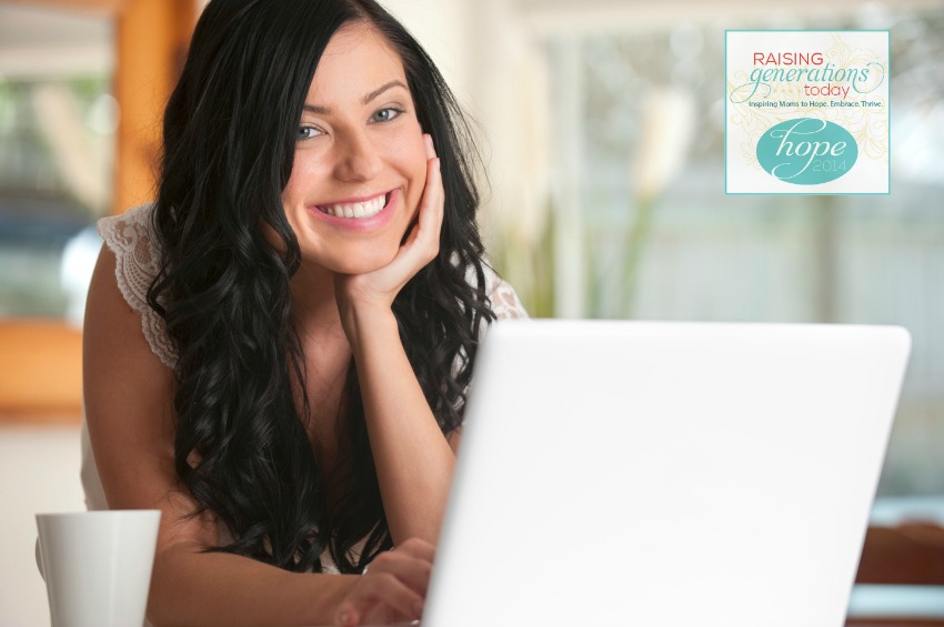 Happy woman looking at a laptop indoors, looking at camera